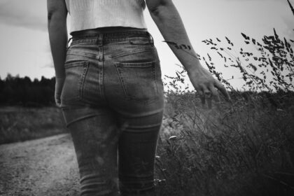 grayscale photo of woman in white tank top and black denim jeans